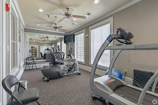 A home gym with a treadmill, exercise bike, and a television.