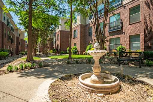 A garden with a fountain in the middle of a courtyard.