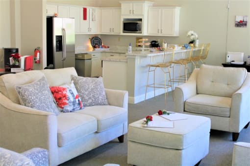 A white couch with a red pillow and a white ottoman with a red rose on it at Clarkston Station Apartments, Clarkston, GA 30021
