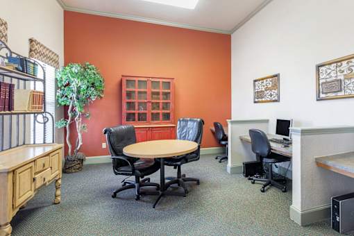 A room with orange walls has a table, chairs, and a bookcase.
