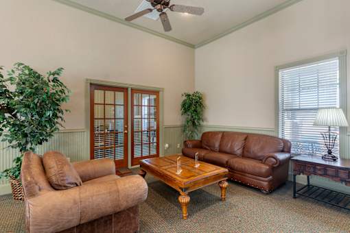 A living room with a brown couch, a wooden coffee table, and a ceiling fan.