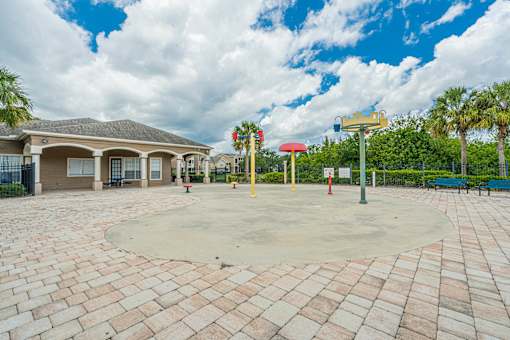 A playground with a red and yellow structure and a brick walkway.