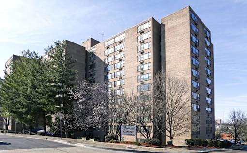 A parking lot in front of a large building with cars parked.