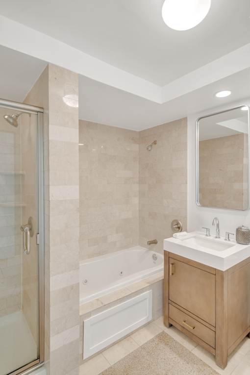 A bathroom with a sink, mirror, and bathtub.