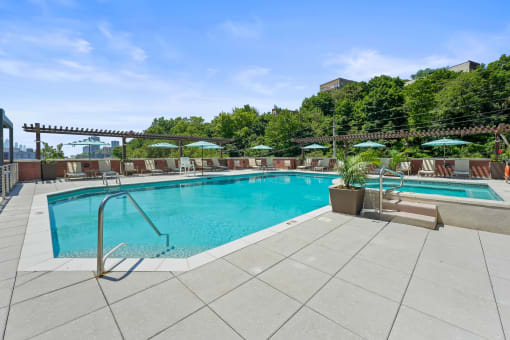 a swimming pool with chairs and umbrellas on a patio next to a pool at Riello Apartments Owner LLC, Edgewater