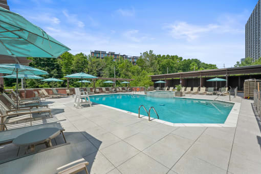 a swimming pool with chairs and umbrellas at a hotel at Riello Apartments Owner LLC, Edgewater, NJ, 07020