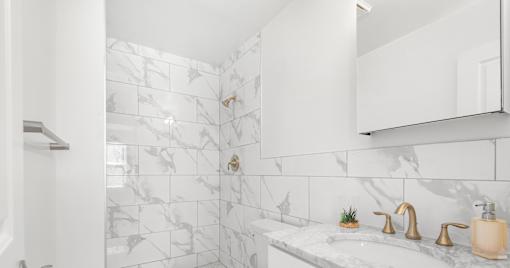 A bathroom with a marble tile shower and sink area.