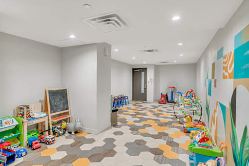 A room with a white ceiling and a colorful floor with toys scattered around.