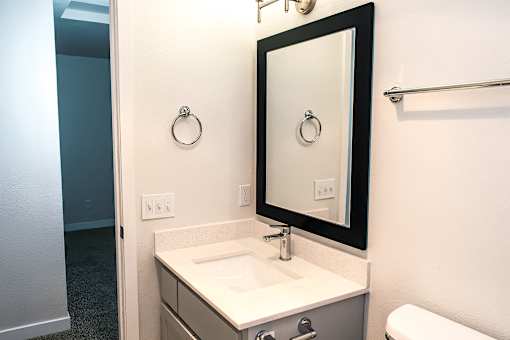 A bathroom with a sink, mirror, and towel rack.