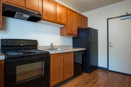 a kitchen with black appliances and wooden cabinets and a black refrigerator