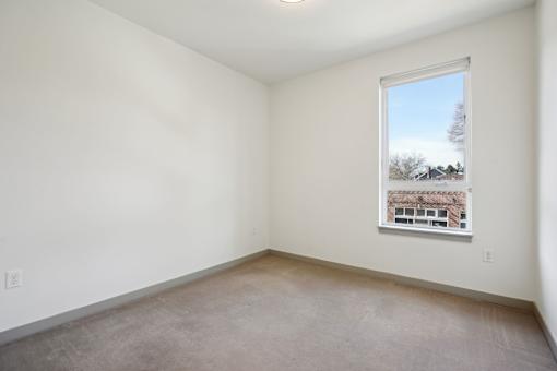A room with a window showing a view of a building outside.