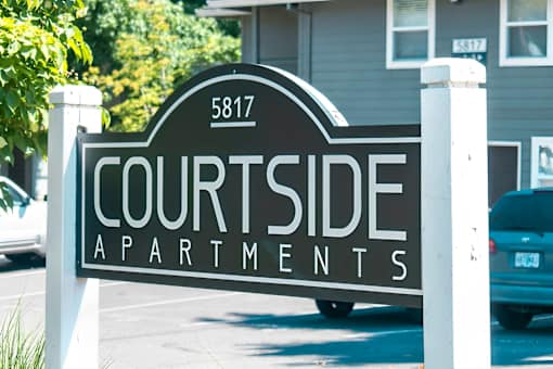 A sign for Courtside Apartments is displayed in front of a building.
