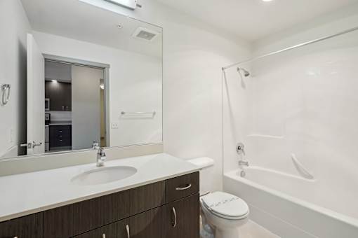 A white sink with a mirror above it and a toilet next to a bathtub.