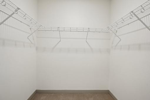A white wire shelf in a white room with a brown floor.