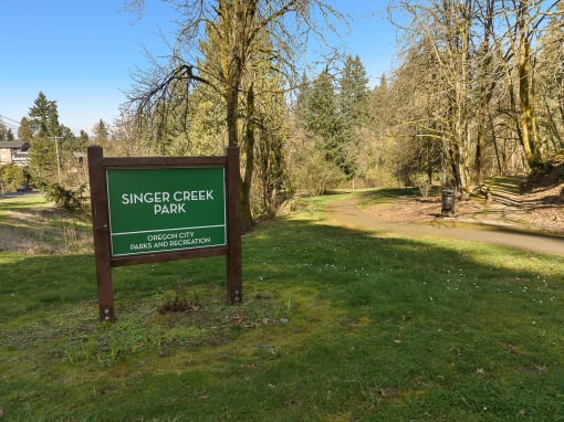 a sign for singer creek park next to a dirt road
