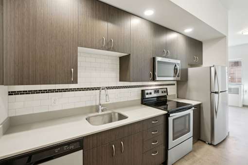 A modern kitchen with dark wood cabinets and stainless steel appliances.