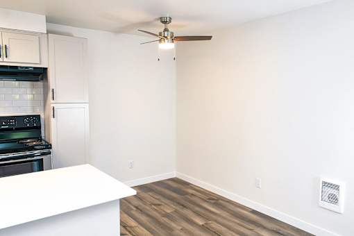 A kitchen with a stove top oven and a fan on the ceiling.