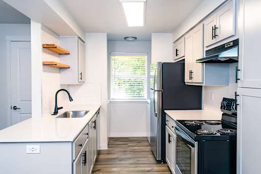 A kitchen with black appliances and white cabinets.