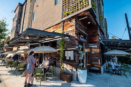 people sitting at tables outside of a restaurant