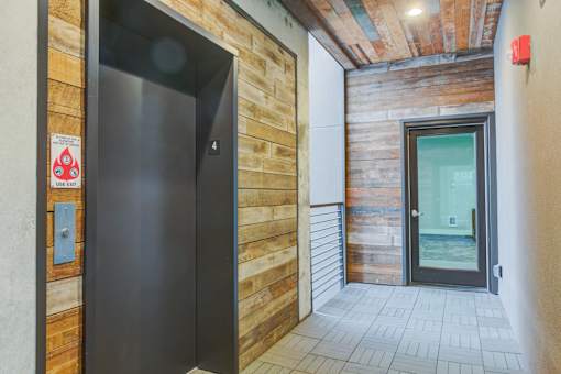 the entrance to a building with a black door and a wooden wall