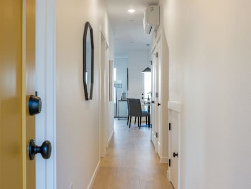 A hallway with a black door and a mirror on the wall.