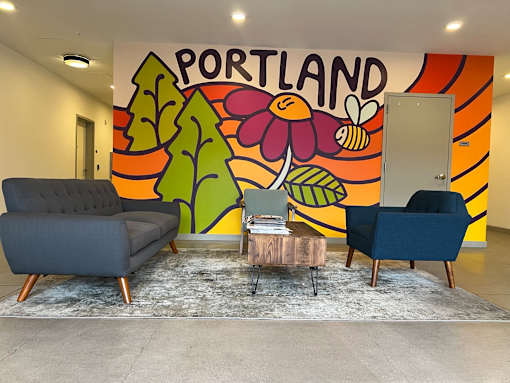 A room with a Portland mural on the wall and two chairs and a table in front of it.