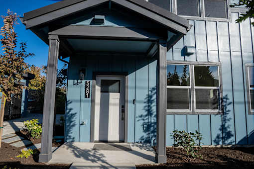 A blue house with a white door and a small porch.