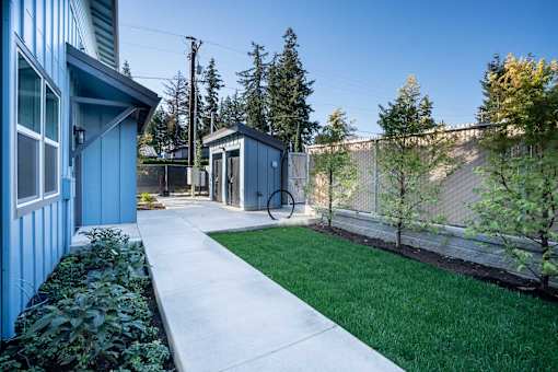 A blue house with a white walkway leading to a small building.