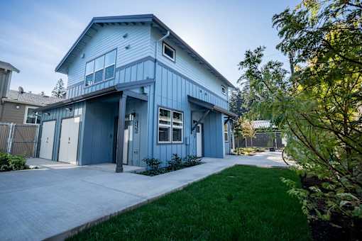 A blue house with a white fence and a green lawn in front.