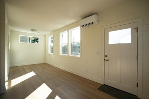 A room with a white door, windows, and a wall-mounted air conditioner.