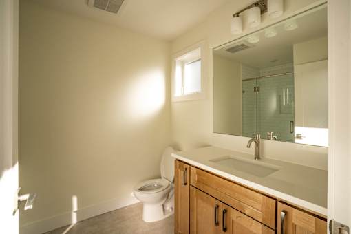 A bathroom with a toilet, sink, and mirror.