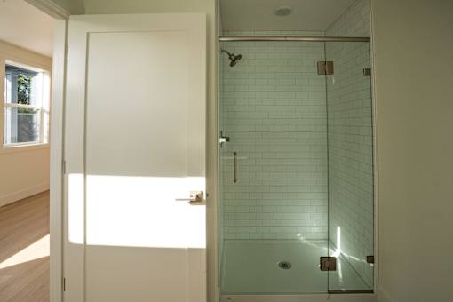 A bathroom with a glass shower stall and a white door.