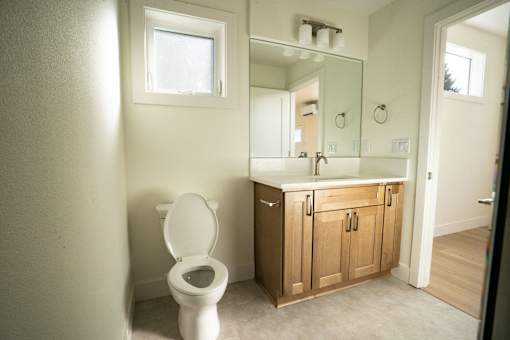 A white toilet sits in a bathroom with a wooden cabinet and a mirror above it.
