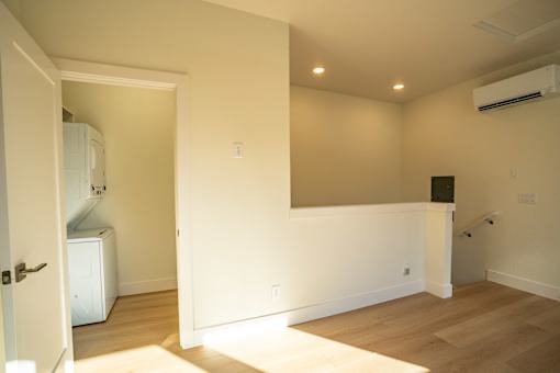 A room with a white door and a white wall with a black speaker on the wall.
