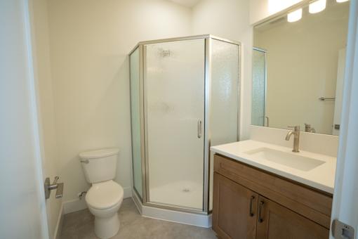 A white toilet sits next to a walk-in shower in a bathroom.