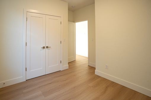 A room with a white door and a wooden floor.