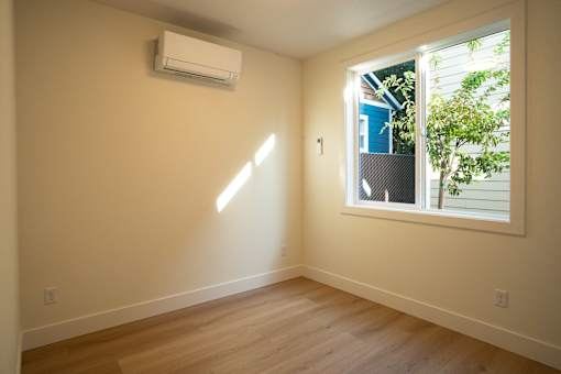 A room with a window and an air conditioner on the wall.