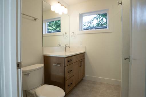 A white toilet sits in a bathroom with a sink and mirror.