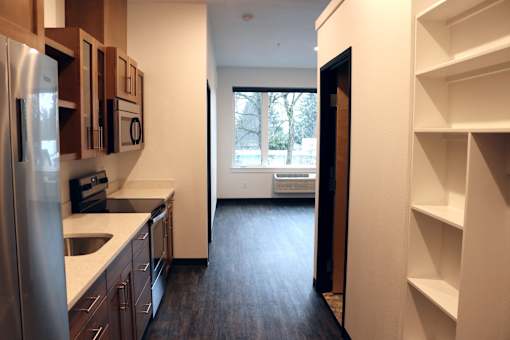 A kitchen with a refrigerator, sink, and cabinets.