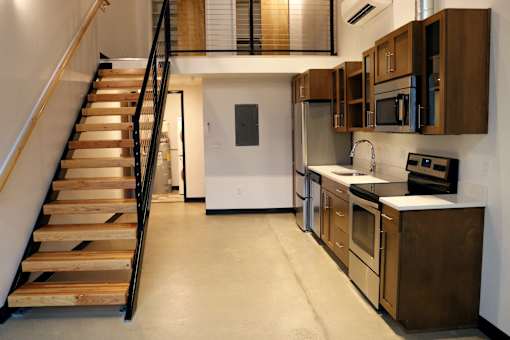 A kitchen with wooden cabinets and a staircase.