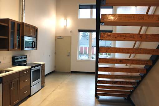A kitchen with wooden cabinets and a staircase.