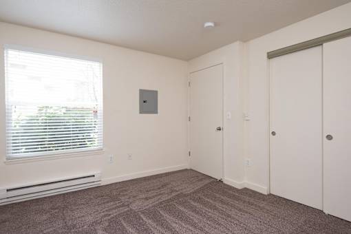 A room with a window, a door, and a wall-mounted thermostat.