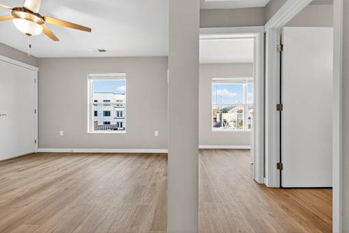 A room with a ceiling fan and wooden flooring.