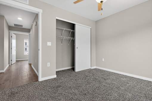 A room with a ceiling fan and a closet with shelves.
