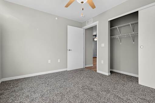 A room with a ceiling fan and a doorway leading to another room.