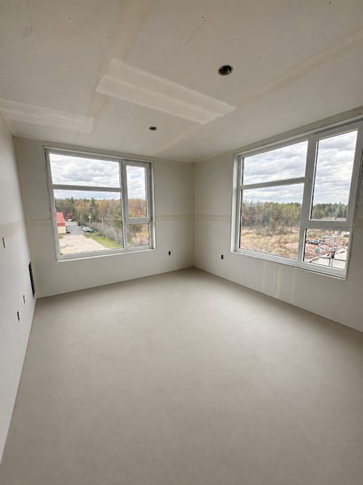 A room with white walls and a large window overlooking a field.