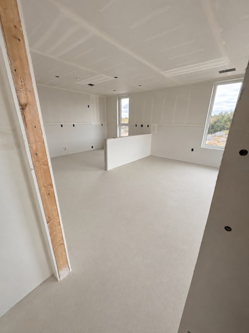 A room under construction with exposed wooden beams and unfinished walls.