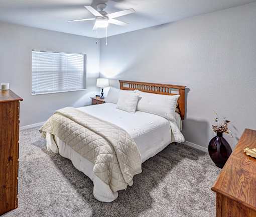 A bedroom with a large bed and a ceiling fan.