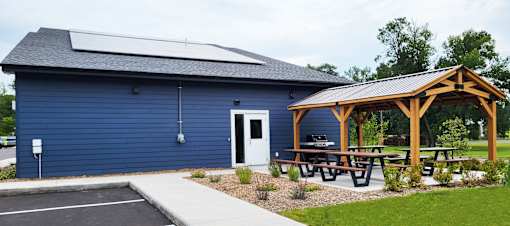 A blue building with a wooden pergola and picnic tables in front.