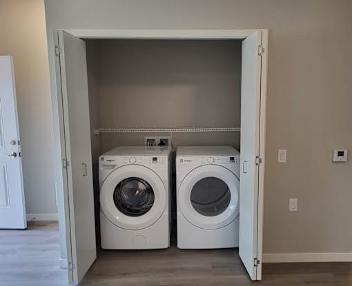 Two white front load washing machines in a laundry room.